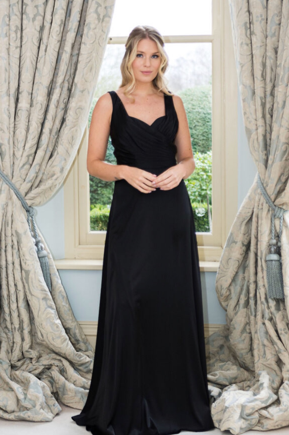 A bridesmaid in a black sweetheart-neckline satin gown
