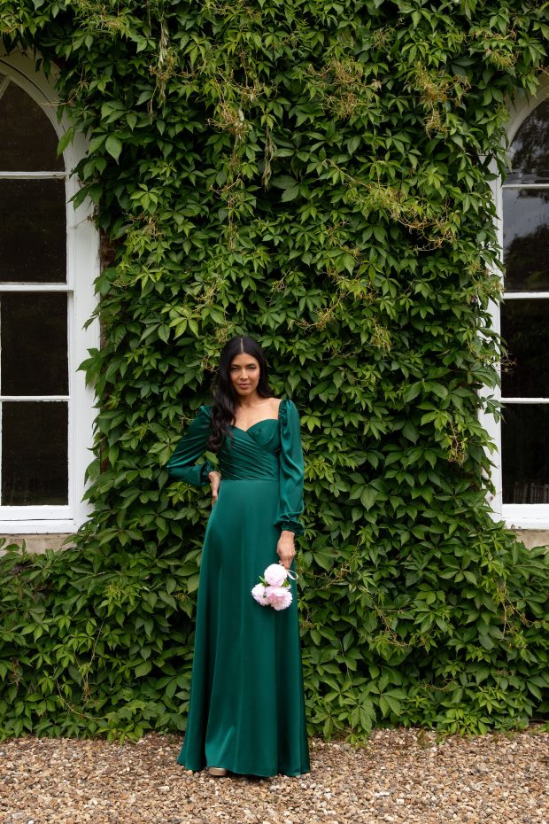A bridesmaid in an emerald-green satin gown with a sweetheart neckline and long puff sleeves