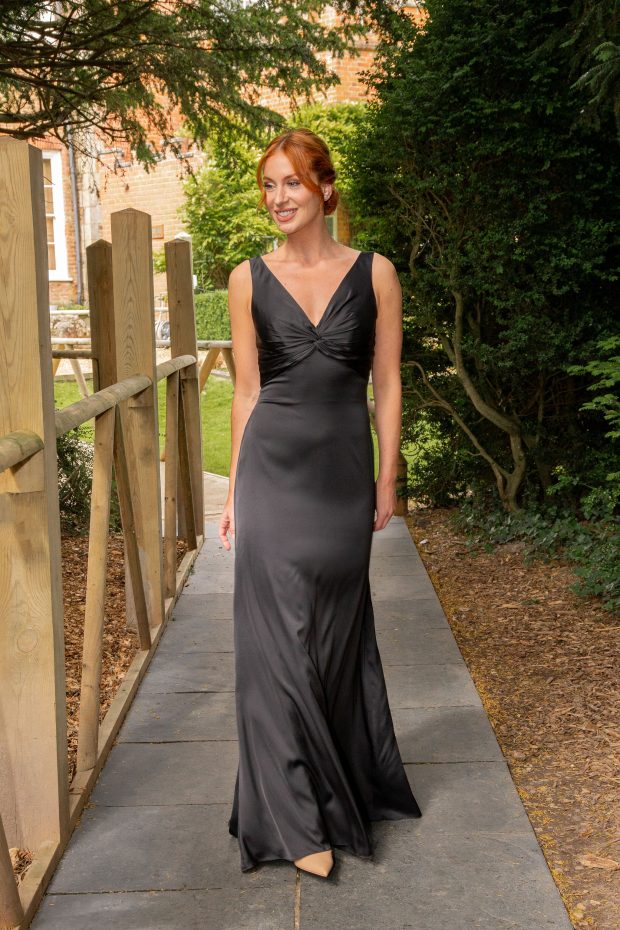 A bridesmaid in a charcoal satin bias-cut gown with a twist-front V-neck