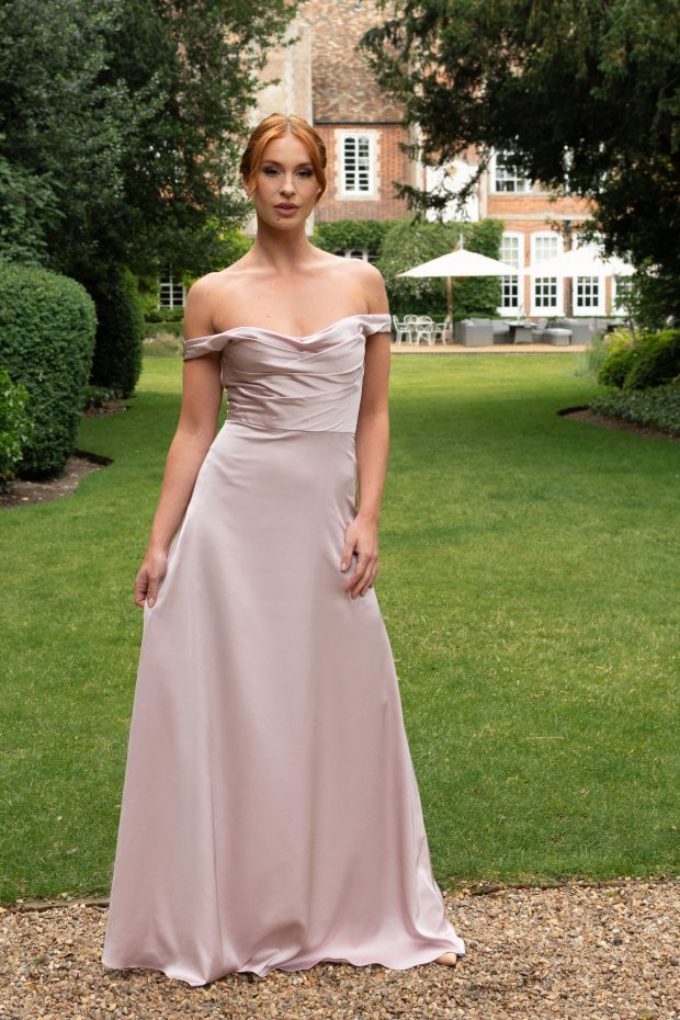 A bridesmaid in a blush-pink off-the-shoulder satin gown with an A-line skirt