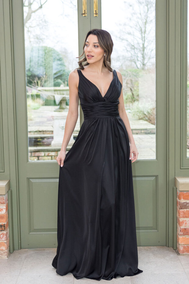A bridesmaid in a black satin gown with a V-neck, ruched waist and full skirt
