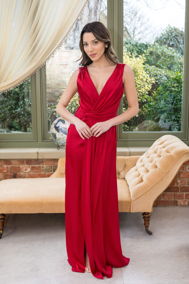 A bridesmaid in a red satin gown with a plunging V-neck and knot-front waist