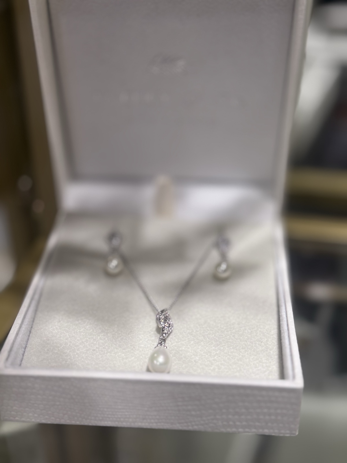 A pearl pendant necklace with matching earrings in a presentation box
