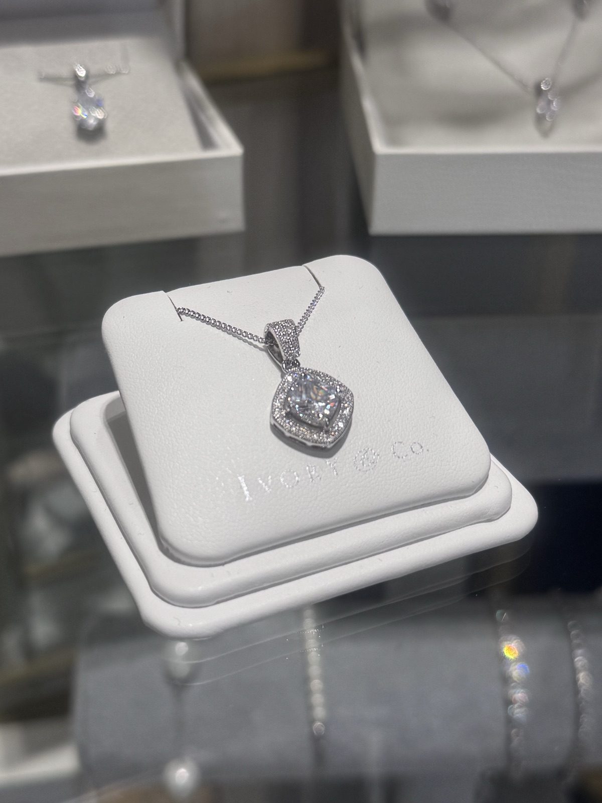 A crystal halo pendant necklace on a display stand