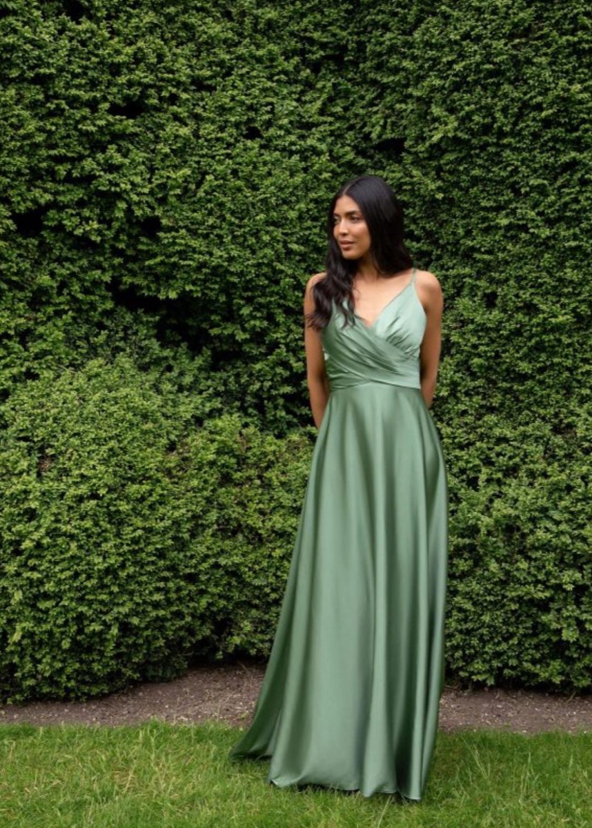 A bridesmaid in a sage-green gown in a garden