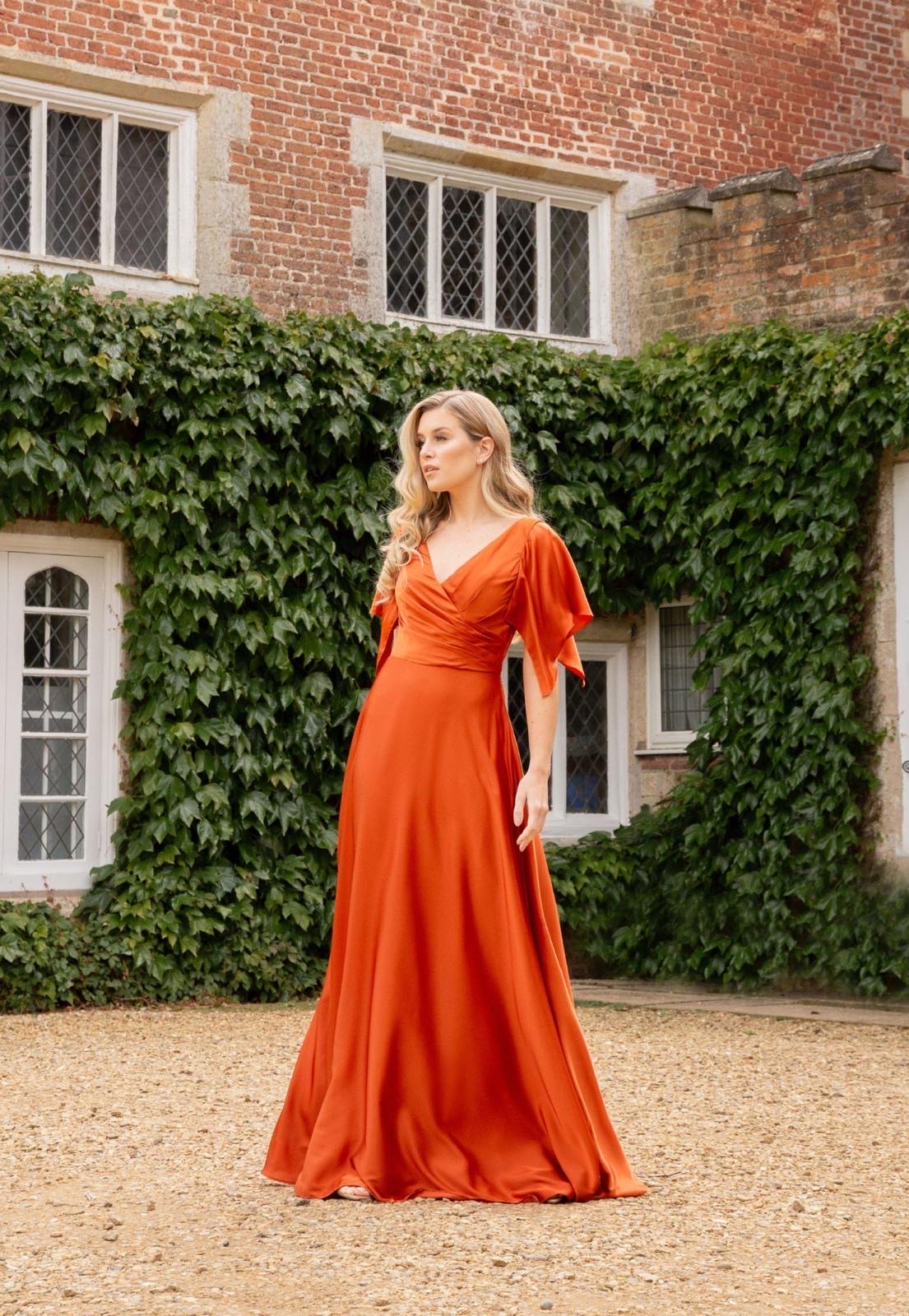 A bridesmaid in a rust satin gown at a country-house wedding venue