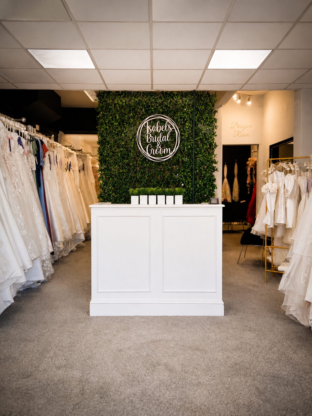 Inside Isobels on Ashley Road, with the branded foliage wall and rails of bridal gowns