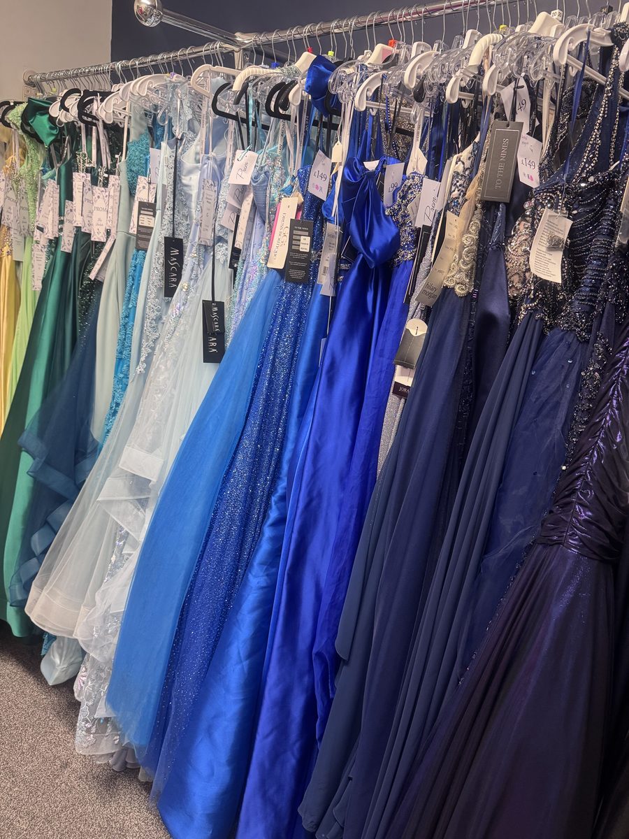 A rail of prom dresses in the Isobels Prom Suite, in greens, blues and navy